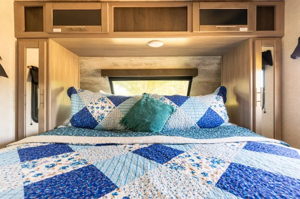 The bed inside River RV, from the foot of the bed toward the pillows